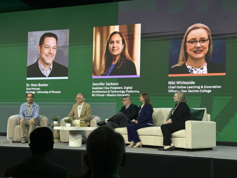 Five people sit on stage during a panel discussion, with three speakers’ portraits, names, and titles displayed on a large screen behind them. The set includes white sofas, chairs, and a green background.